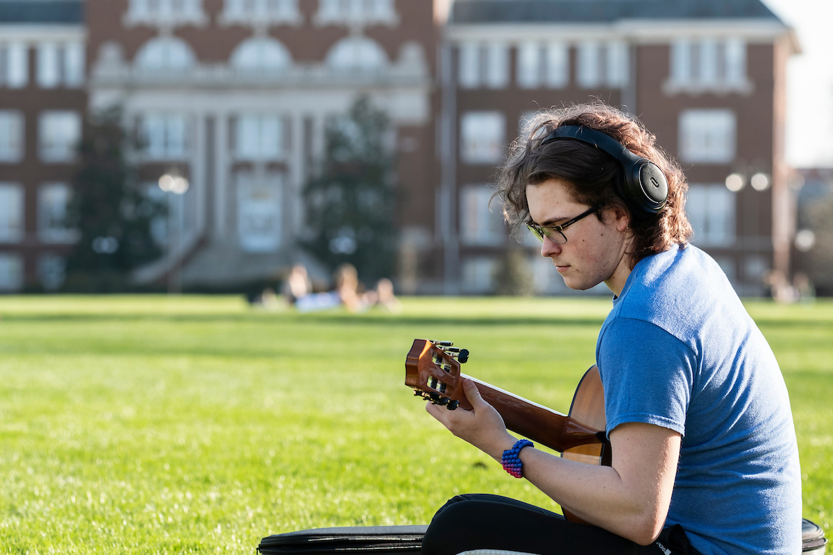 A student playing guitar on the drill field