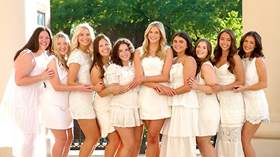 Group photo of Issy Karp and nine others in white dresses on the MSU campus.